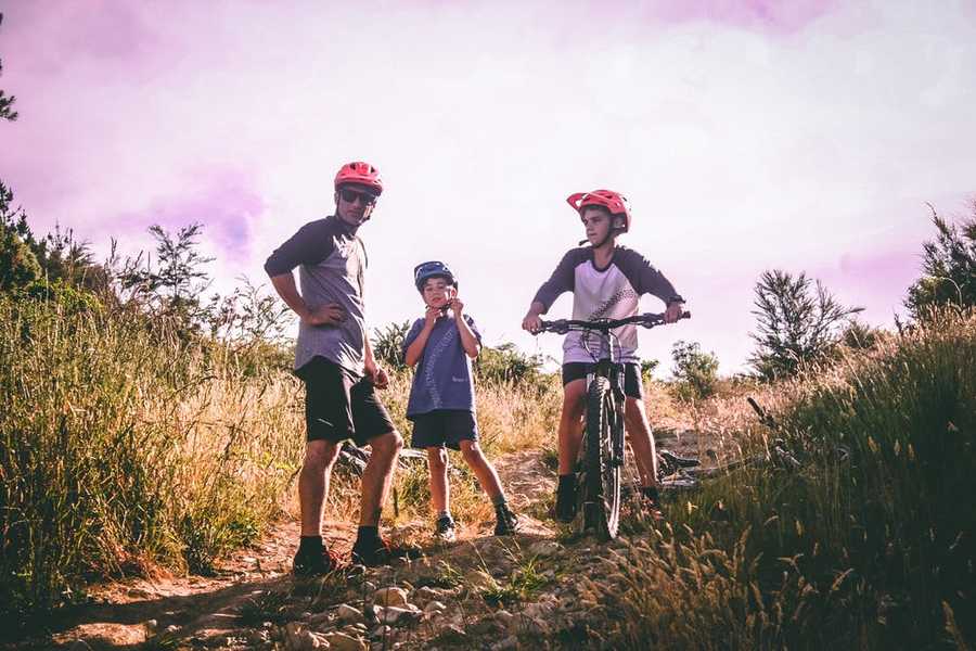 photo un père et ses deux fils avec casque de vélo dans la campagne